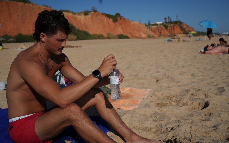 Opening a bottle of water on the beach